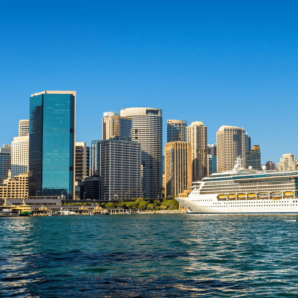 A cruise ship in the water with a city in the background