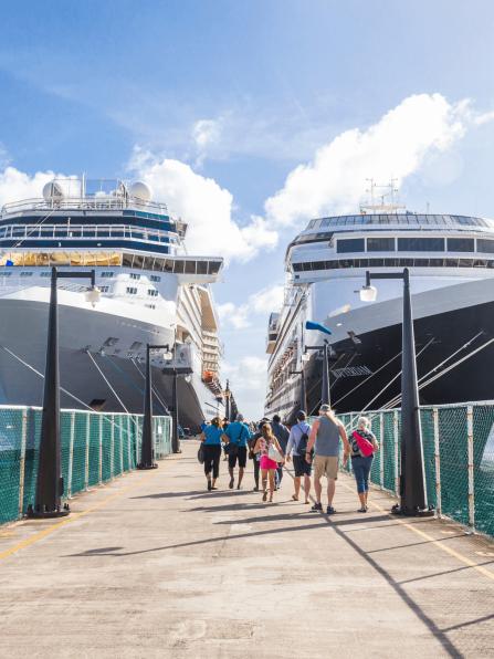 People walking on a pier next to two cruise ships